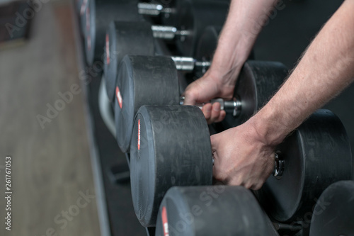 Colorful images. Hands holding dumbbells in the gym.