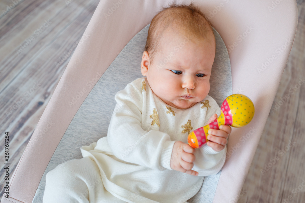 Adorable baby girl having fun in bouncer. Toddler playing with colorful rattle toy. Activities for infants Adorable baby girl having fun in bouncer. Toddler playing with colorful rattle toy. Activities for infants