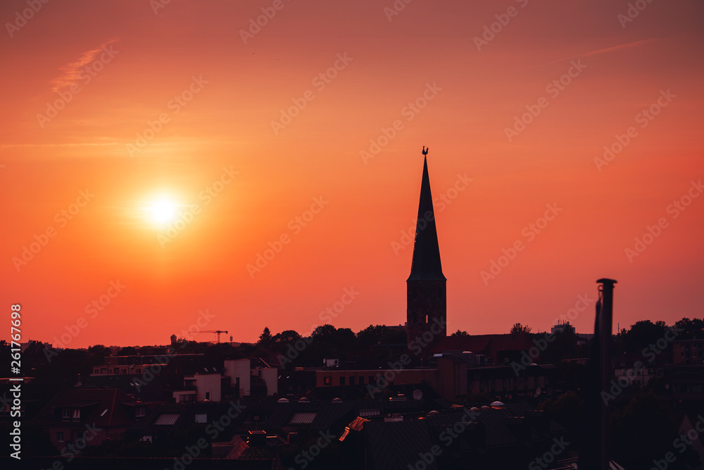 Beautiful and colorful summer sunset roof top view of a old historic church tower above the city. Warm red and orange sky color tones. Old town of Braunschweig, Germany