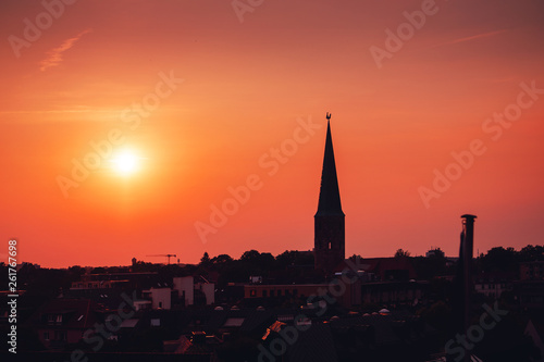 Beautiful and colorful summer sunset roof top view of a old historic church tower above the city. Warm red and orange sky color tones. Old town of Braunschweig, Germany