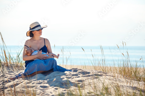 Young mother holding her newborn child. Mom nursing baby in nature