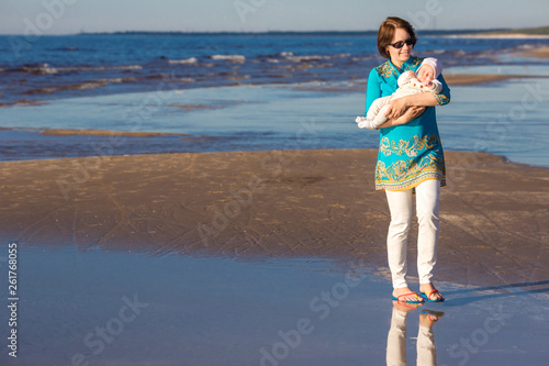 Canvas Print Young mother and her cute little baby girl playing on a beautiful summer beach