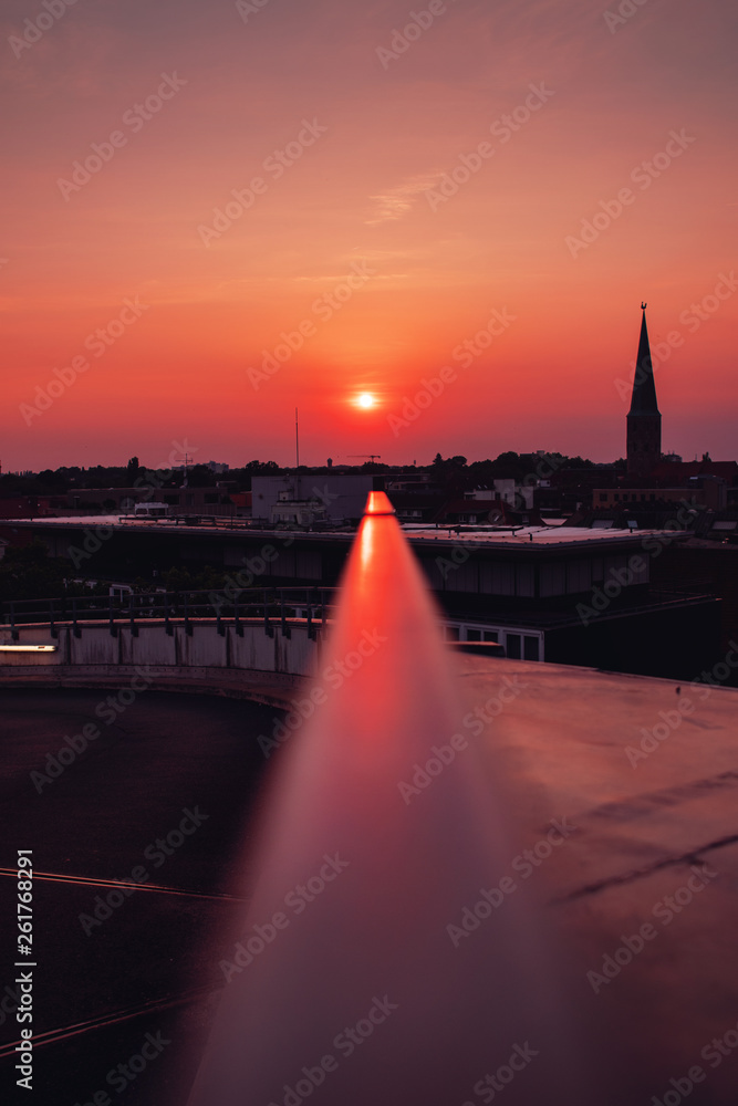 Obraz premium Urban Park deck rooftop view with Glass structure and church on the horizon with sunset light reflection on the metal. Colorful warm summer light view. Old town of Braunschweig, Germany