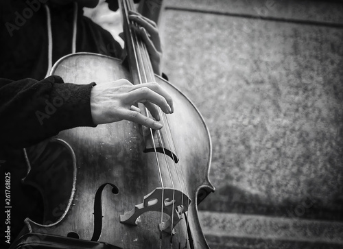 Street musician or busker playing upright bass in urban city environment.