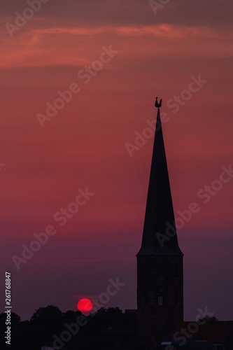 Beautiful and colorful summer sunset roof top view of a old historic church tower above the city. Warm red and orange sky color tones. Old town of Braunschweig, Germany © Ricardo