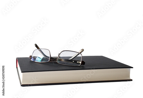 Book or novel with pair of reading glasses spectacles resting on it isolated on white.