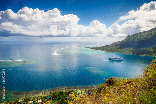 Panoramic lagoon view from the top of the hill Mount Rotui. Paradise Beach coastline seascape with boat, road and palm trees at Moorea, Tahiti French Polynesia