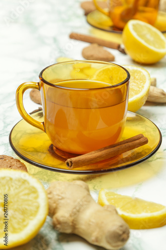 A yellow cup of tea, with ginger roots, lemon and spices. A healthy lifestyle, anti-flu and anti-inflammatory concept.