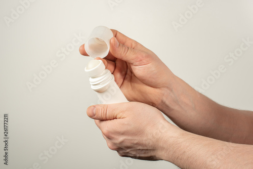 Male hands holding deodorant for armpits on a white background