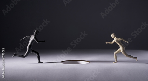 Two men run towards a big hole. Isolated on gray background. Studio Shot. With space copy text. © Serge Aubert