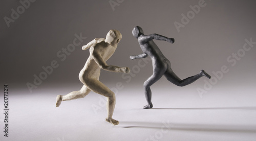 Black and white men run in different directions. With space copy  text. Isolated on grey background. Studio Shot. © Serge Aubert
