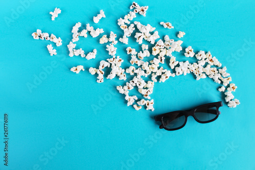 Cinema time on blue paper background. Abstract fun active image of viewer, 3D glasses, popcorn. Concept cinema movie and entertainment. Flat lay composition copy space