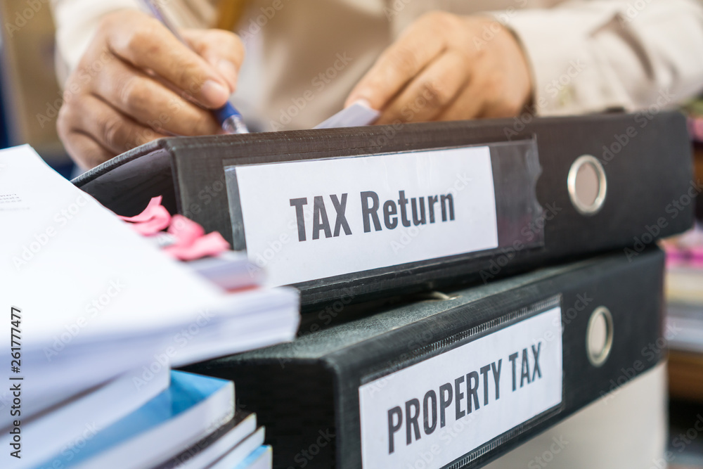 Tax return and property tax folders stack with label black binder on paperwork documents summary report in busy offices by manager checking. HR-human resources business bookkeeping accountancy Concept Tax return and property tax folders stack with label black binder on paperwork documents summary report in busy offices by manager checking. HR-human resources business bookkeeping accountancy Concept