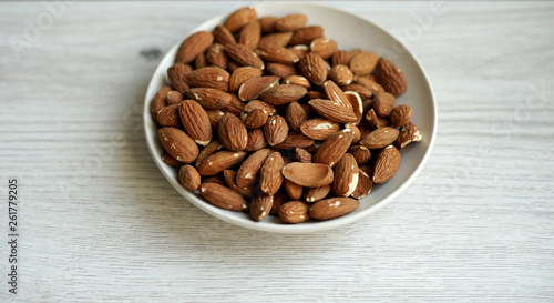 Healthy food  for background image close up almond nuts. Texture on white grey table top view. Nut on the cup plate