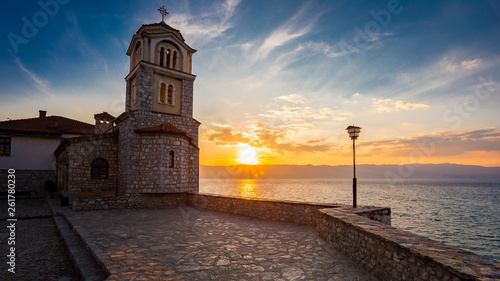 Colorful sunset with clouds over Ohrid`s lake, christian monastery Saint Naum photo