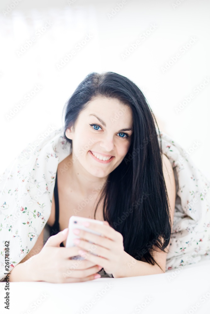 Black haired sexy woman relaxing and using cell phone on bed. Black haired sexy woman relaxing and using cell phone on bed.