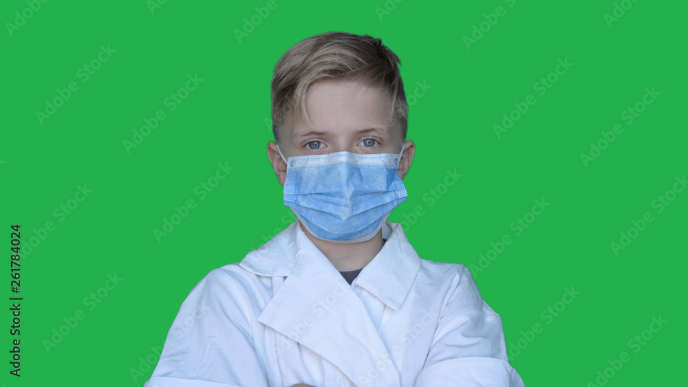 In slow motion on the background of a chromakey a young guy (boy) in a doctor's uniform in a mask. Concept of: Green background, Chromekey, Young doctor, Fashionable, Blond, Doctor. In slow motion on the background of a chromakey a young guy (boy) in a doctor's uniform in a mask. Concept of: Green background, Chromekey, Young doctor, Fashionable, Blond, Doctor.