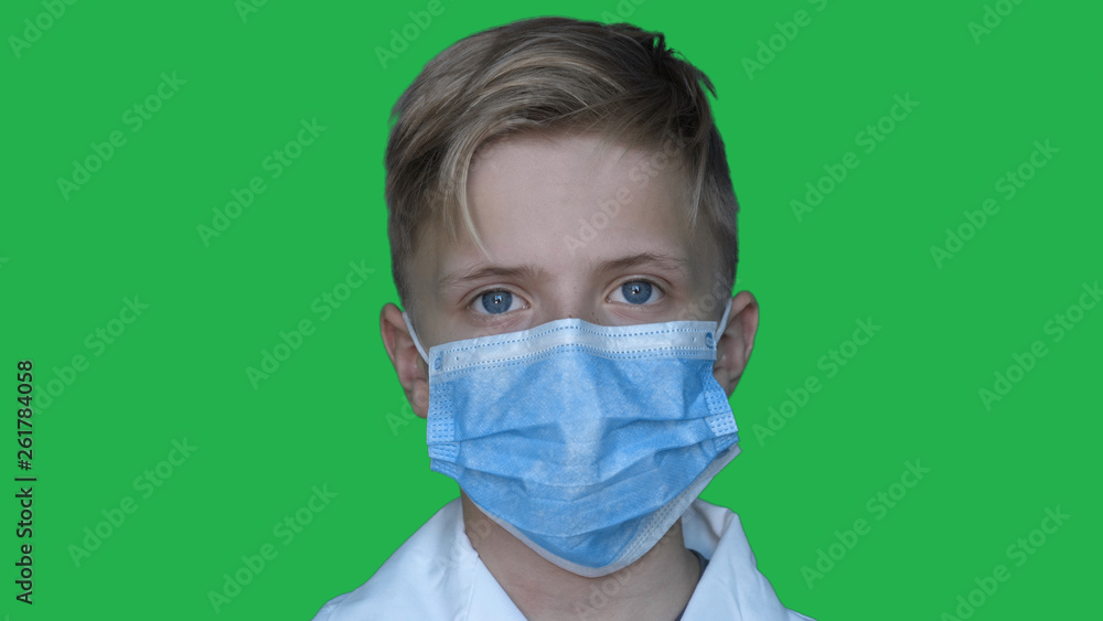 In slow motion on the background of a chromakey a young guy (boy) in a doctor's uniform in a mask. Concept of: Green background, Chromekey, Young doctor, Fashionable, Blond, Doctor. In slow motion on the background of a chromakey a young guy (boy) in a doctor's uniform in a mask. Concept of: Green background, Chromekey, Young doctor, Fashionable, Blond, Doctor.