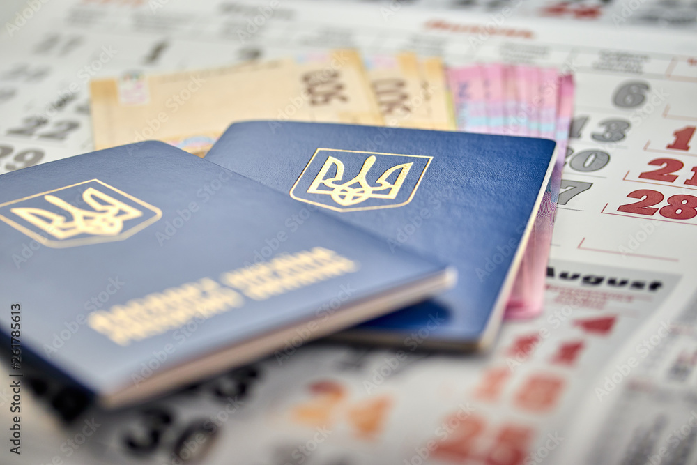 passports with national currency paper money close up view of cash on a calendar background passports with national currency paper money close up view of cash on a calendar background
