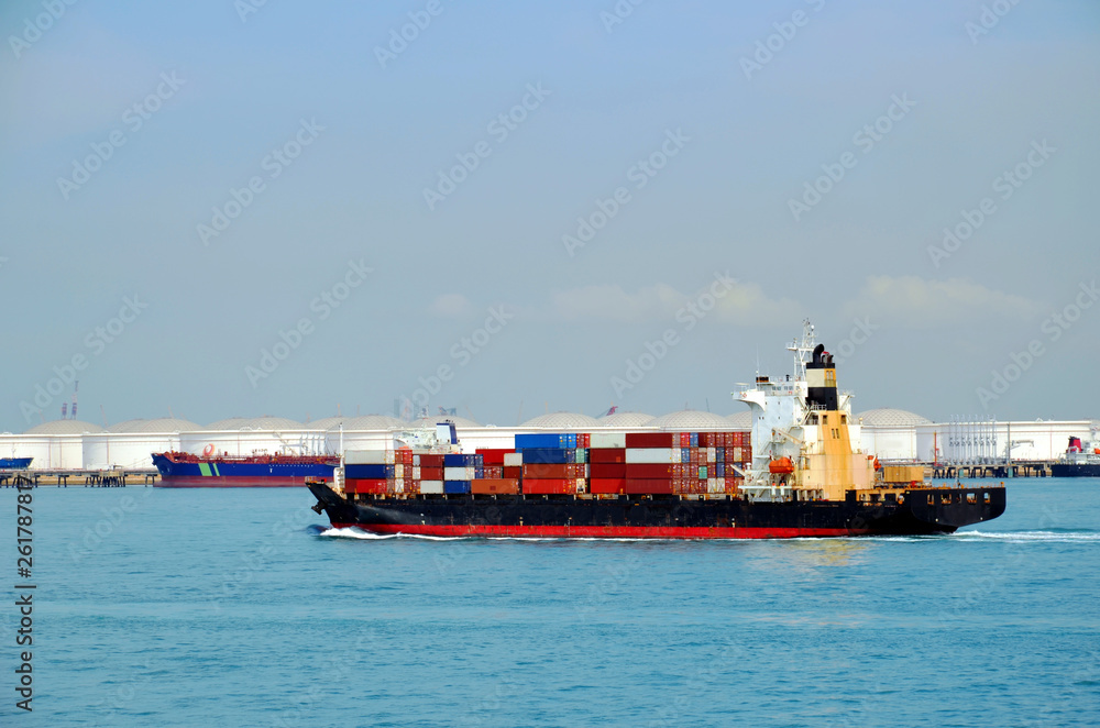 Container ship departing from Singapore industrial area.