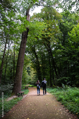 young couple walking by city park holding hands