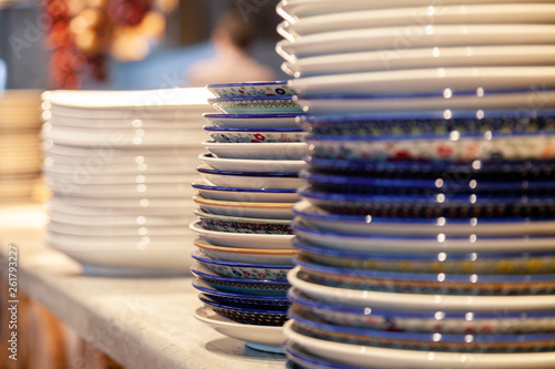 Closeup stack white and colored blue porcelain plates with oriental and ethnic ornament stands in open kitchen of trendy restaurant. Concept washing dishes  preparing for lunch  evening service