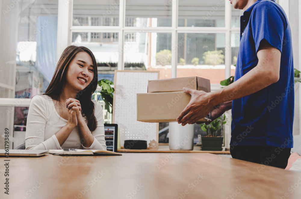 smart home delivery service man in blue uniform and pretty young asian  woman customer happy smiling and receiving parcel post box from courier at  home, express delivery, online shopping concept Stock Photo