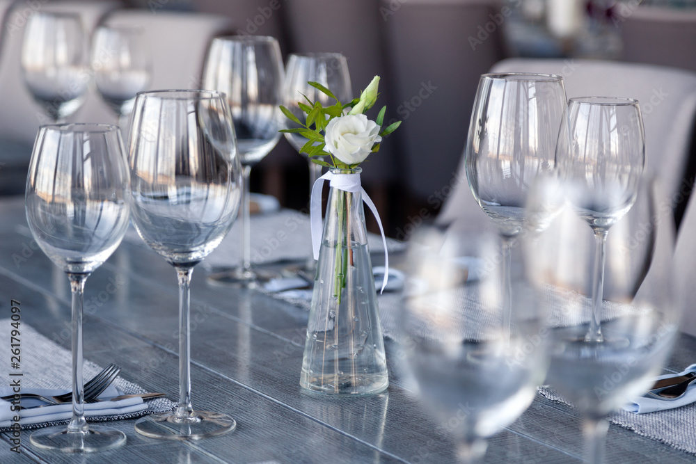 Modern restaurant setting, glass vase with bouquet flowers on table in restaurant. Wine and water glasses stand on wooden table. Concept banquet, birthday, conference, wedding Modern restaurant setting, glass vase with bouquet flowers on table in restaurant. Wine and water glasses stand on wooden table. Concept banquet, birthday, conference, wedding