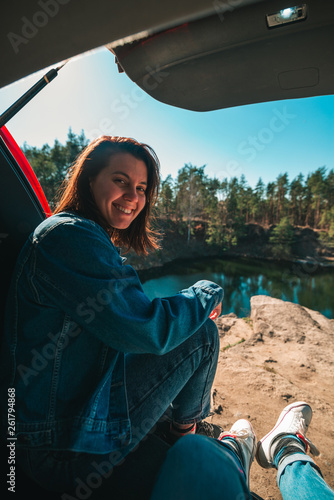 couple in car trunk with beautiful view of lake. first person view. young smiling woman