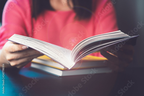 Young woman is reading a book at home. Blurred background. Horizontal, film effect.