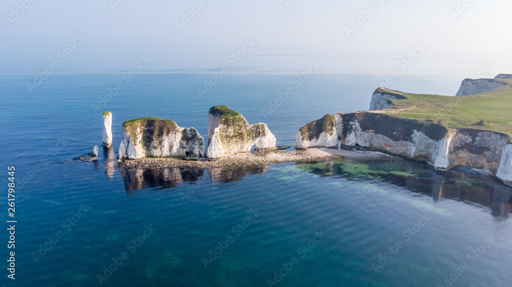 An aerial view of the Old Harry Rocks along the Jurassic coast with crystal clear water and white cliffs under a hazy sky