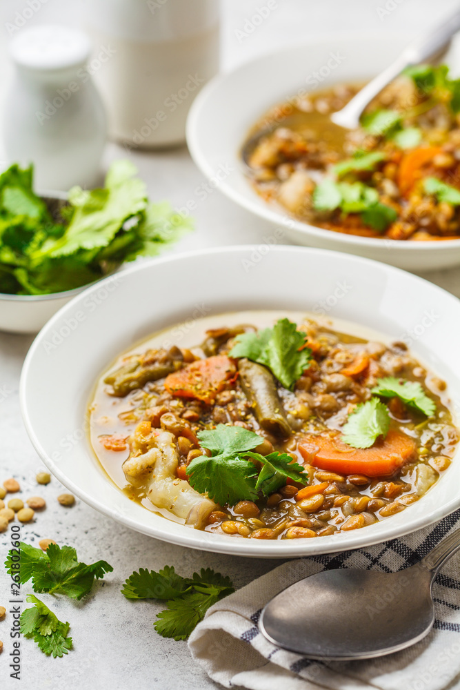 Lentil soup with vegetables in a white plate, white background, vertical. Plant based food, clean eating. Lentil soup with vegetables in a white plate, white background, vertical. Plant based food, clean eating.
