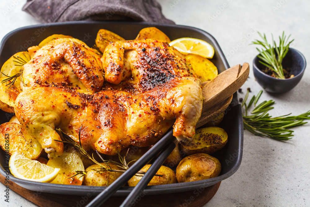 Fried whole tabaka chicken with potatoes in a grill pan, top view, white background. Fried whole tabaka chicken with potatoes in a grill pan, top view, white background.