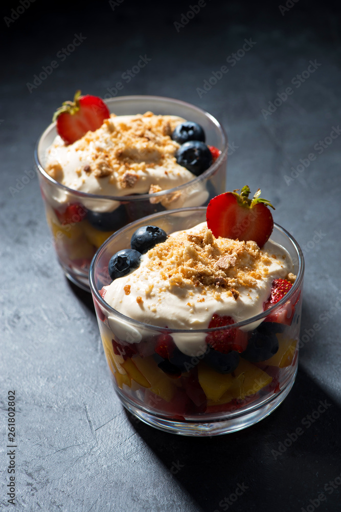 fresh fruit with custard in glasses on a dark background, vertical fresh fruit with custard in glasses on a dark background, vertical