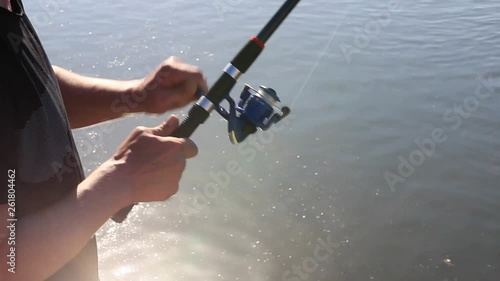 The fisherman turns the coil. Fisherman pulls the fish. Fisherman catches fish. Fishing. A fish. Fishing rod. Fisherman. Catching. River. Water. Hook. Close-up. Arms.