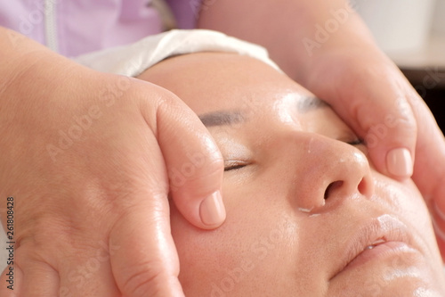 Close-up massage of a Asian female. Smoothing wrinkles on the woman's face. Face and body care in the beauty salon.