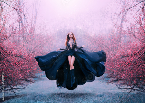 Valokuva gorgeous red-haired hot woman in long flying black dress fluttering, witch turns