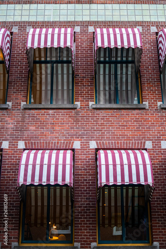 Brick wall building and window with red/white striped sunshade
