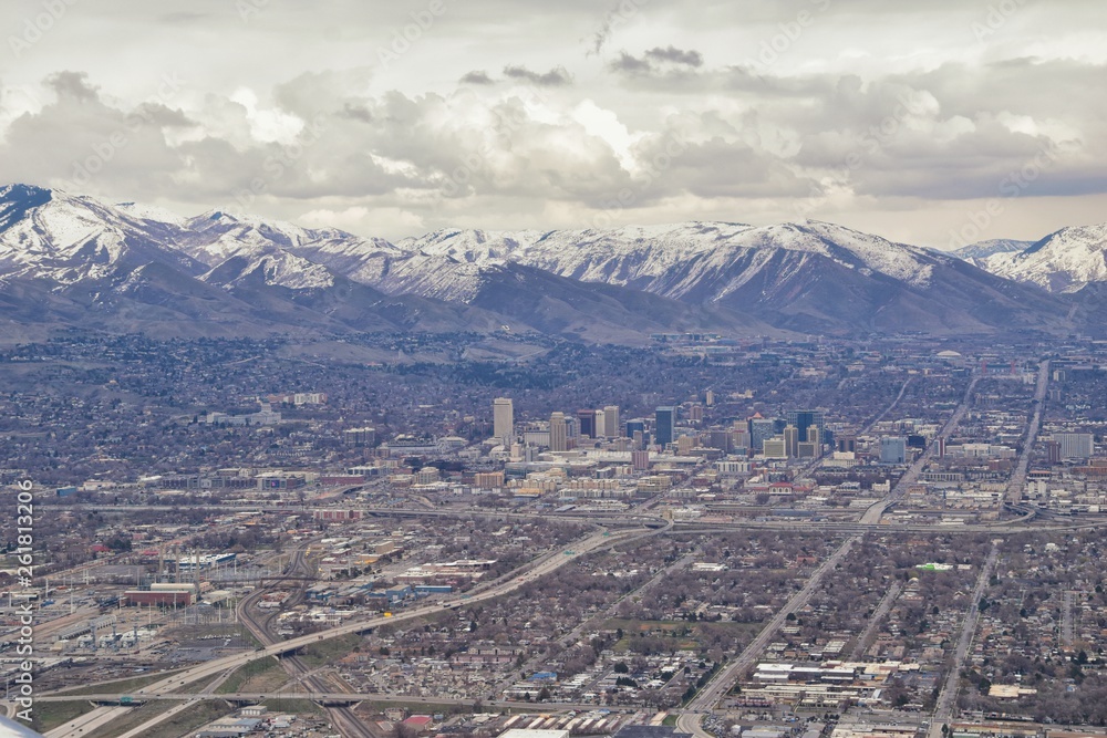 Downtown Salt Lake City Panoramic view of Wasatch Front Rocky Mountains from airplane in early spring winter with melting snow and cloudscape. Utah, USA.