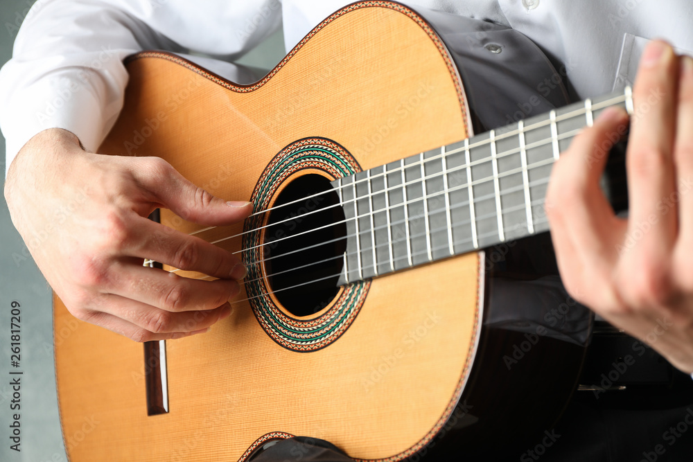 Fototapeta Man playing on classic guitar against light background, space for text