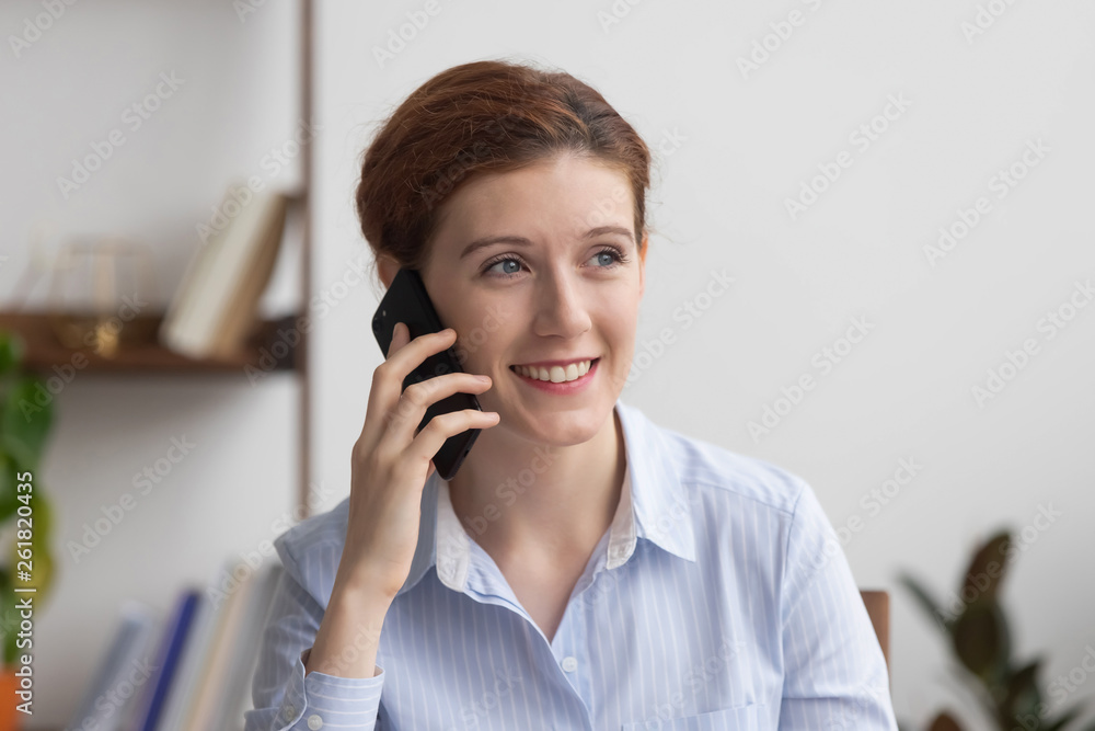 Smiling millennial businesswoman talking on phone in office at work Smiling millennial businesswoman talking on phone in office at work