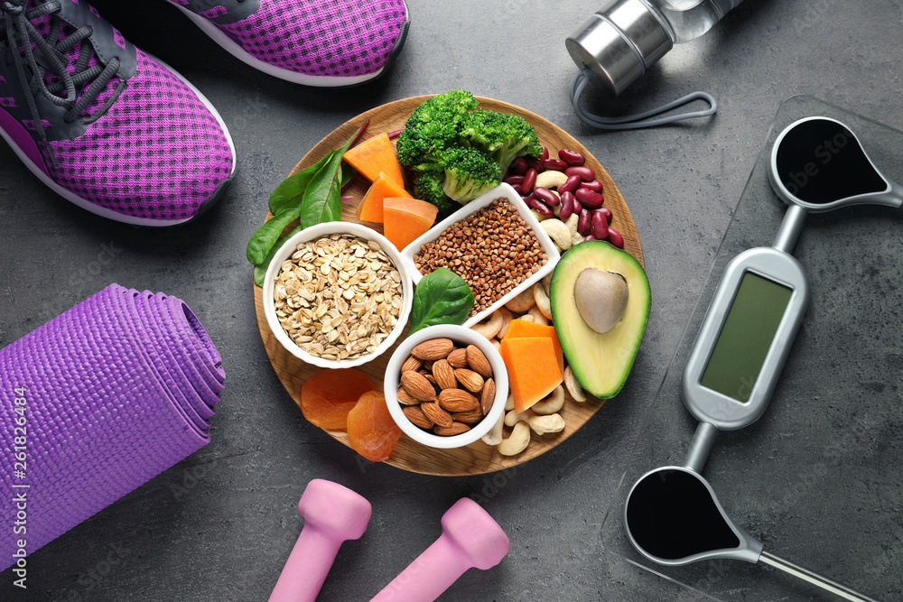 Plate with heart-healthy products and sports equipment on grey background, flat lay