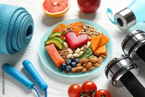Fototapeta Naklejka Na Ścianę i Meble -  Plate with heart-healthy products and sports equipment on wooden background