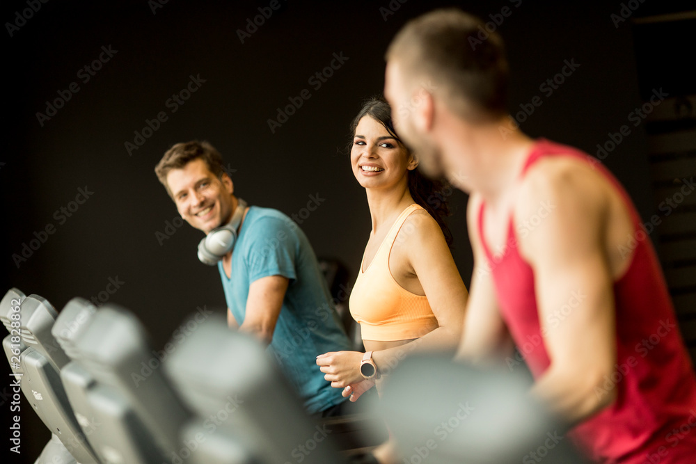 young people running on treadmills in modern gym young people running on treadmills in modern gym