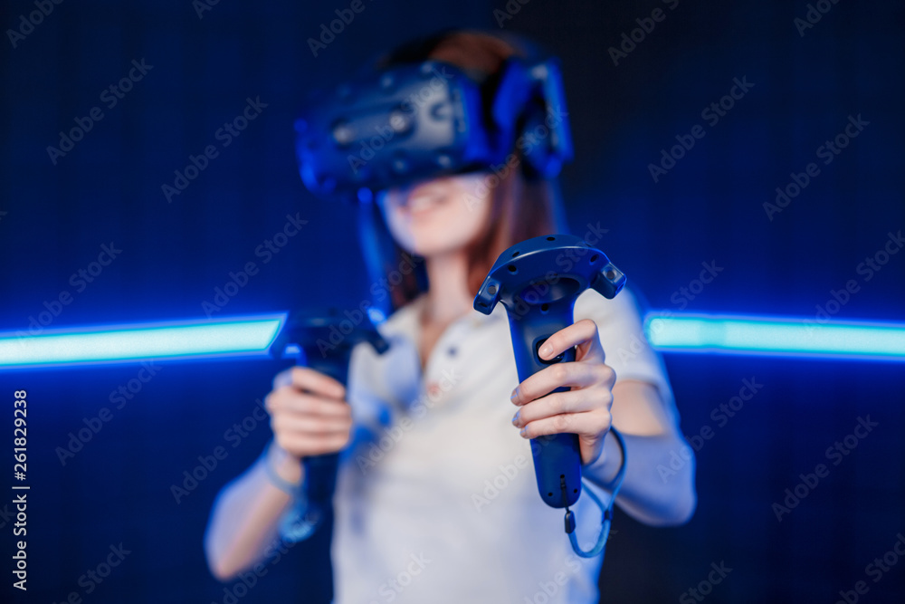 A young girl in a virtual reality helmet in the game room is playing a video game. A young girl in a virtual reality helmet in the game room is playing a video game.