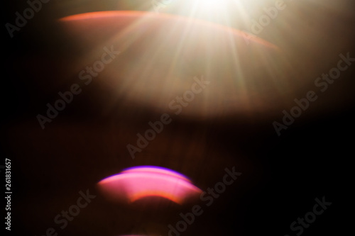 Lens Flare. Light over black background. Easy to add overlay or screen filter over photos. Abstract sun burst with digital lens flare background. Gleams rounded and hexagonal shapes, rainbow halo.