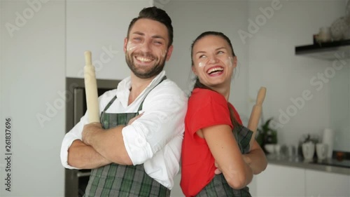 Horizontal Portrait of Surprised Female Leans At Husbands Shoulder Being Shocked That He Is Not Tired After Helping To Prepare Pizza, Has Confidence And Strength. Couple Work As Team On Kitchen.