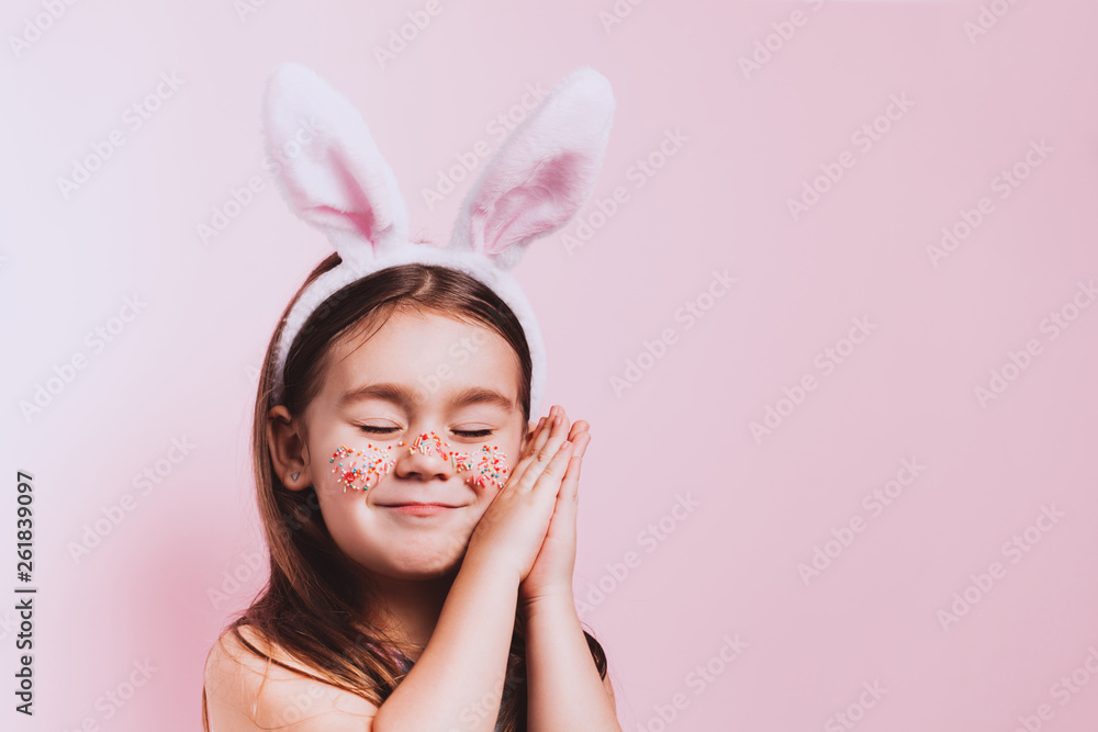 Cute little girl with bunny ears on pink background. Easter child portrait, funny emotions, surprise. Copyspace for text.