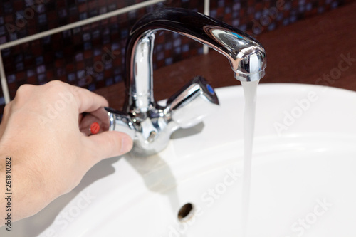 faucet with heat water flow. man turn on water.water flow and save concept.