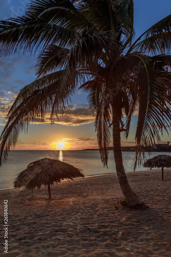 Rancho Luna caribbean beach with palms and straw umrellas on the shore, sunset view, Cienfuegos, Cuba